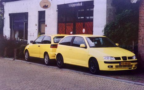 Twee gele lesauto's van Autorijschool Hartkamp voor het huis van de rijschool in 1999